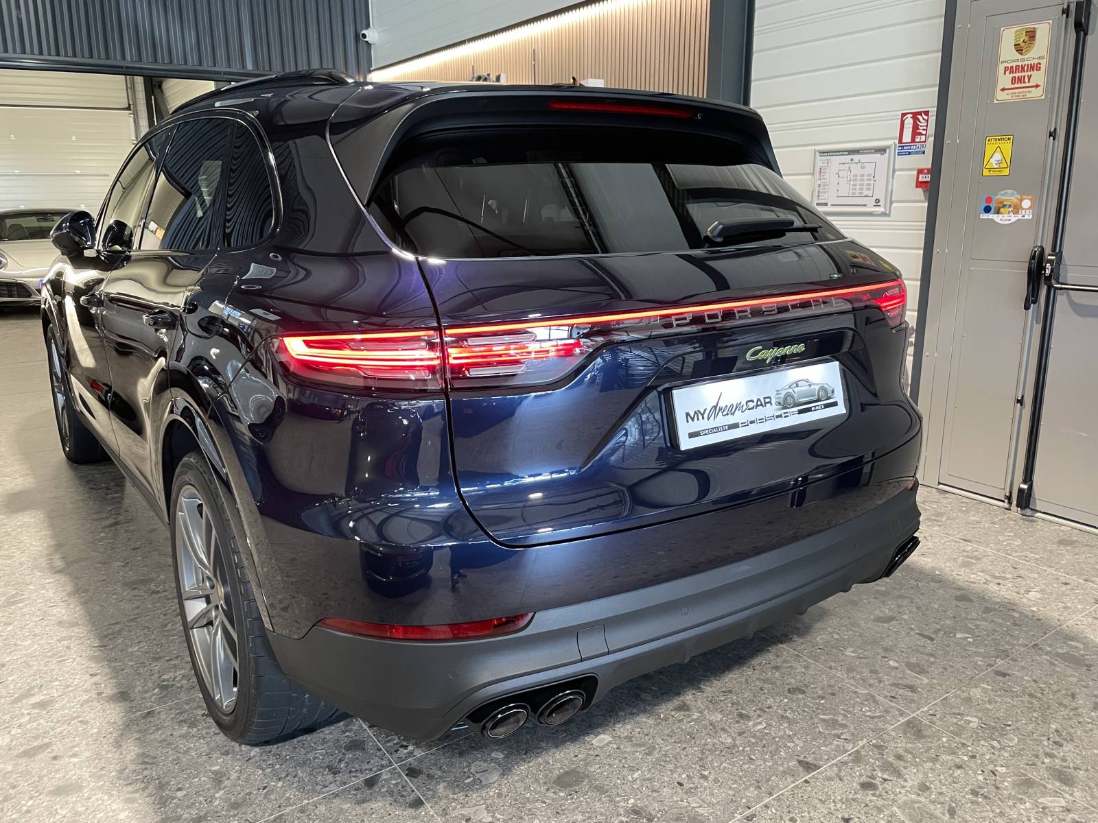 Vue de trois-quarts arrière : SUV Porsche Cayenne 462 ch avec feux LED teintés et bandeau lumineux.